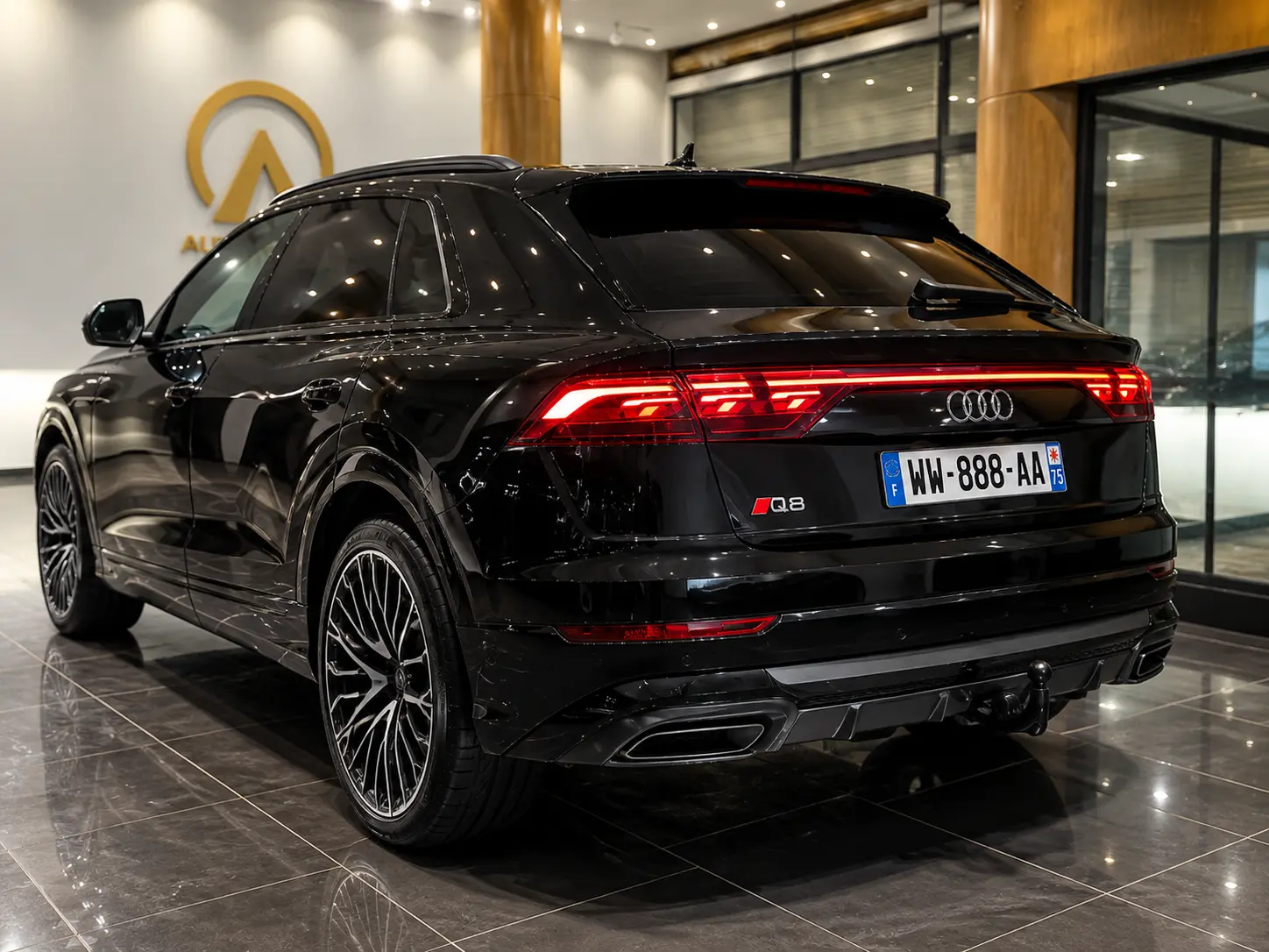 Audi Q8 noire photographiée de l’arrière en trois-quarts dans un showroom automobile moderne avec feux LED allumés