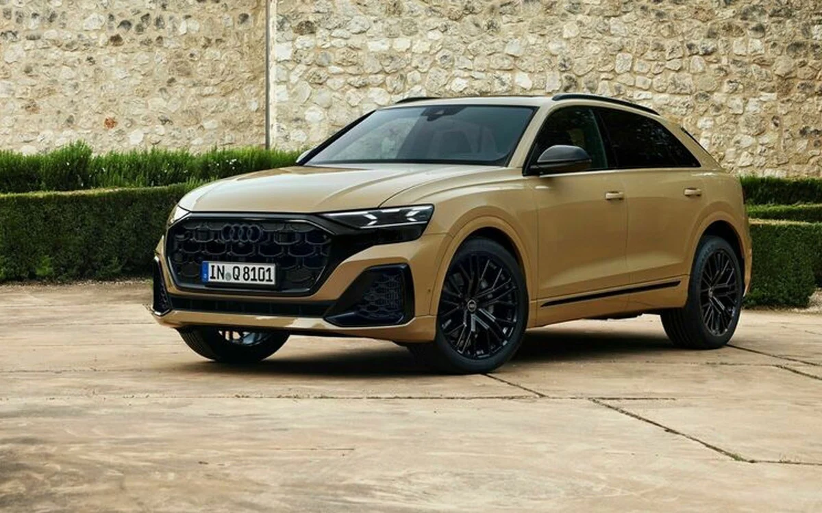 Audi Q8 SUV dorée stationnée dans une rue urbaine, vue avant trois-quarts avec calandre noire et jantes noires